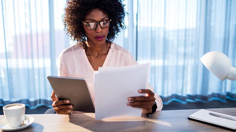 businesswoman looking at a tablet and documents