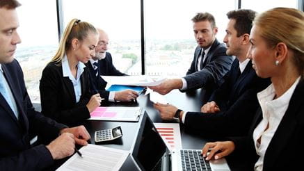Mixed group of people in business meeting working with documents and computers